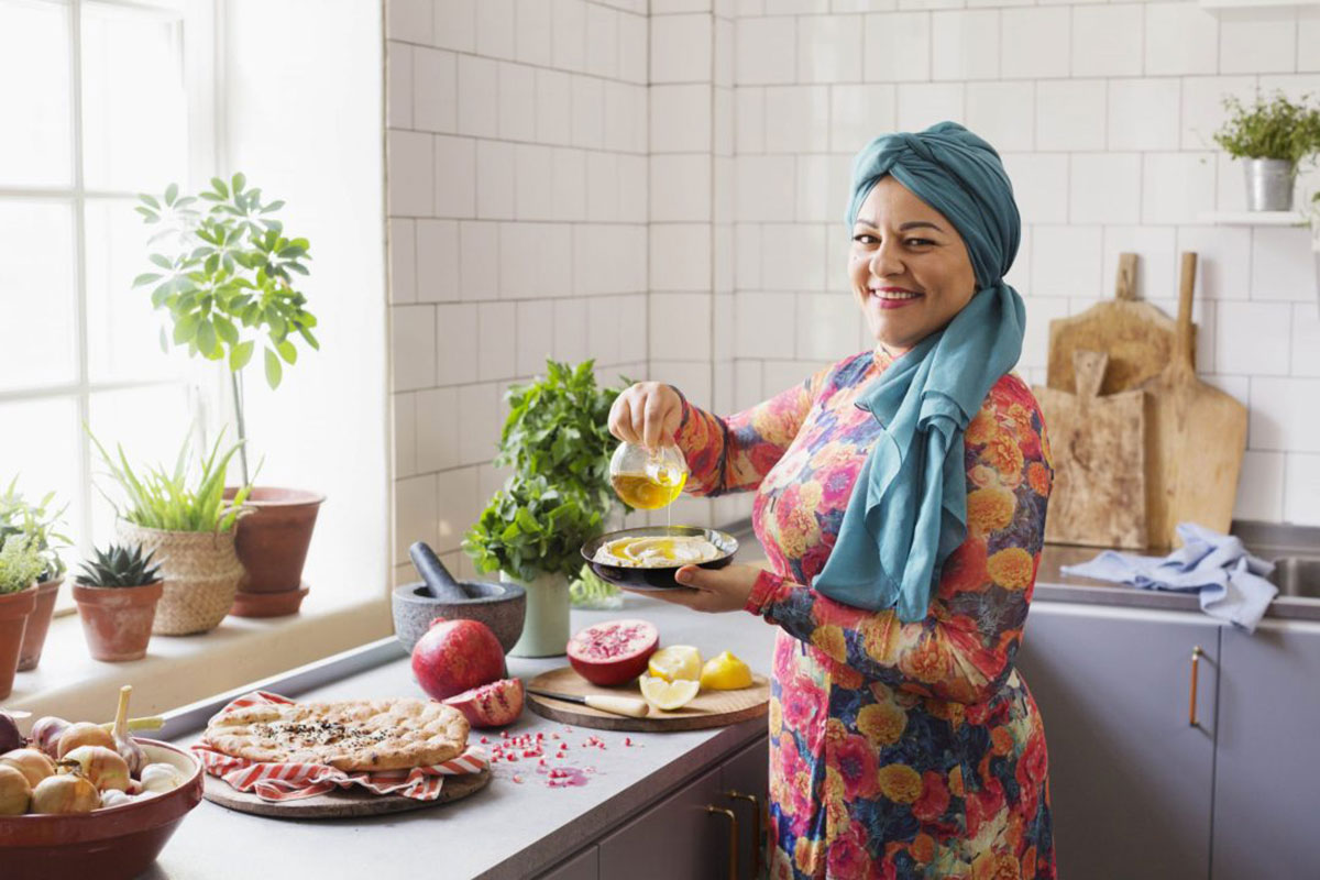 En bild på Zeina Mourtada som lagar mat i köket.