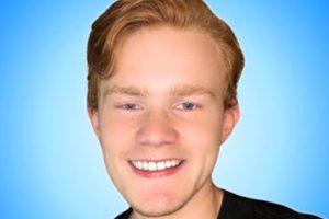 En profilbild på Perik som ler med en blå bakgrund.